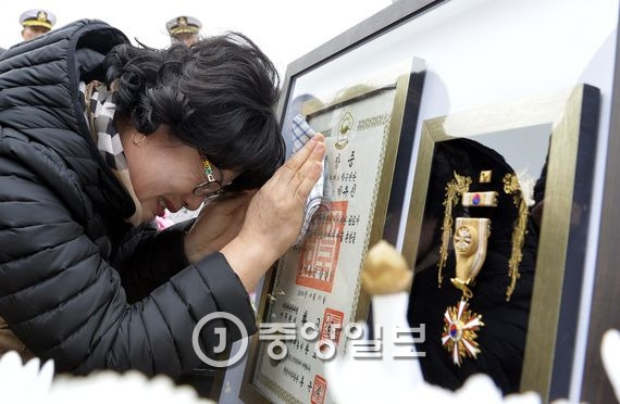 고 박유신 소령의 유족이 5일 국립대전현충원에 안장된 고인의 무덤 앞에서 같은 날 받은 훈장을 보며 눈물을 흘리고 있다. 대전=프리랜서 김성태