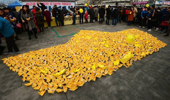 지난달 31일 서울 광화문광장에서 열린 '송박영신' 10차 촛불집회에서 시민들이 세월호를 상징하는 노란색 종이배를 놓고 있다./ 사진제공=뉴스1