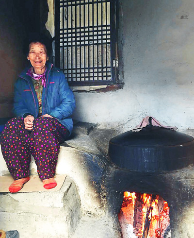 아홉 살때 시집 와 80년 가까이 이 마을에 살고 있는 이금선 할머니가 아궁이 옆에 앉아 있다.