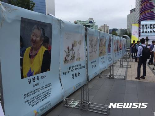 【서울=뉴시스】안채원 기자 = 14일 서울 종로구 청계광장에서 제5차 세계 일본군 위안부 기림일을 맞아 '기림일, 인권과 평화로 소녀를 기억하다' 행사가 열렸다. 한 시민이 행사장 한편에 마련된 위안부 피해자의 사진과 그림 작업을 바라보고 있다.