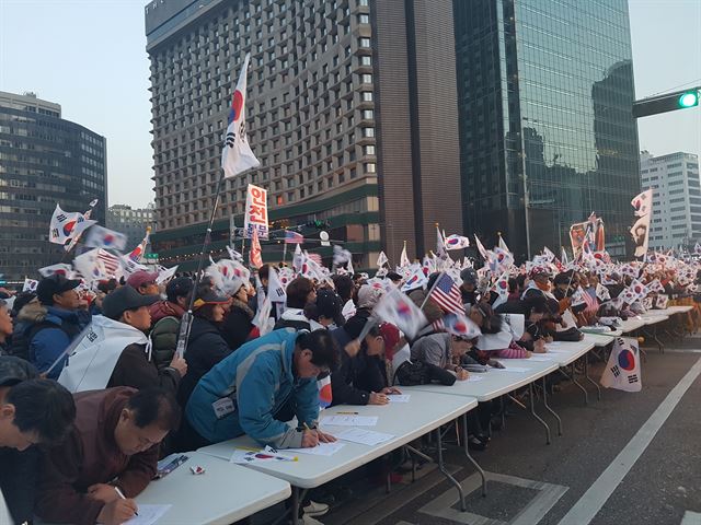 11일 오후 서울 중구 대한문 앞에서 탄핵 무효 집회 참가자 십여 명이 새누리당 가입 원서를 쓰고 있다. 정반석 기자