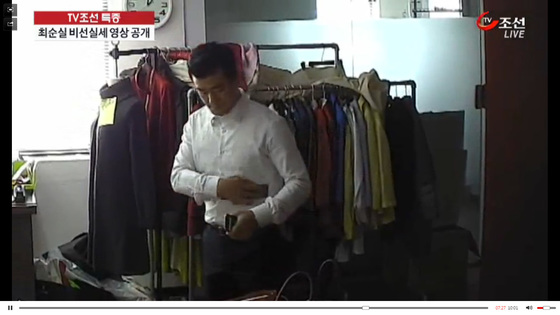 이영선 전 행정관이 최순실씨의 사무실에서 휴대전화기를 자신의 셔츠에 닦고 있다. 그 뒤 그는 전화기를 최씨에게 건넸다.  [사진제공=TV조선 캡처]