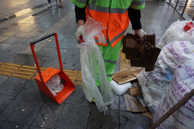 지난 7일 서울 마포구 번화가. 환경미화원 이모(53) 씨가 우산 비닐 커버를 치우고 있다. [사진=박로명 기자/dodo@heraldcorp.com]