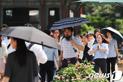 서울이 39도까지 치솟으며 기상 관측 111년 만의 최악의 폭염이 예고된 1일 오후 서울 광화문 네거리에서 시민들이 양산을 쓴 채 이동하고 있다. 2018.8.1/뉴스1 © News1 허경 기자