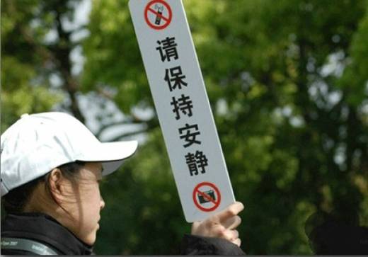 “정숙해주세요” 팻말을 든 여행 가이드