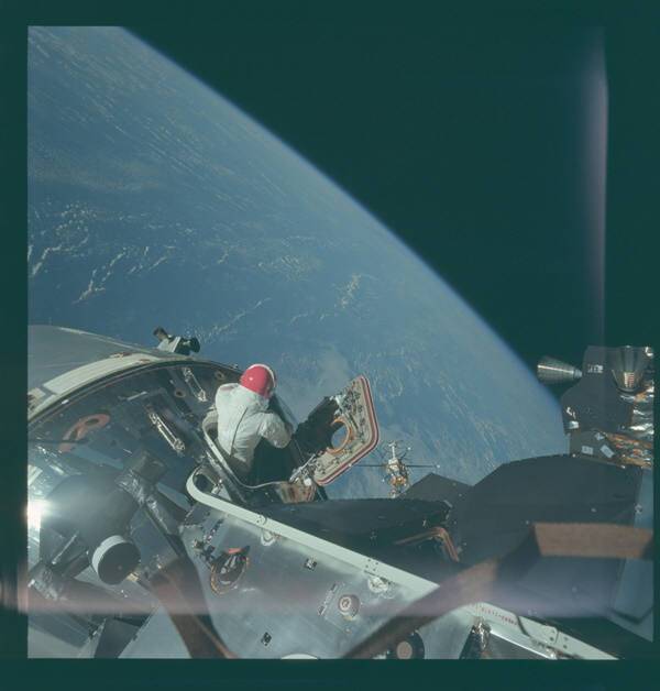 아폴로9호 우주비행사가 우주유영을 위해 우주선 밖으로 나오고 있다. 배경은 지구다. 사진=나사