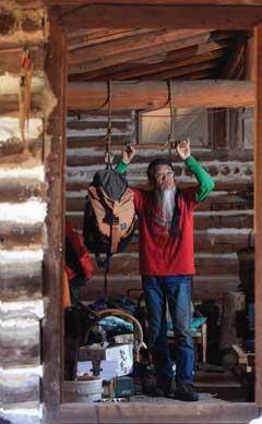 [월간산]턱걸이를 위해 매달아 놓은 나무 봉을 잡고 있다. 그의 집에는 오래된 등산 장비와 다양한 책, 음악 감상을 위한 음반으로 가득 차 있다.