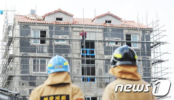 15일 제주시 도남동 한 아파트 공사장에서 한 인부가 밀린 임금을 달라며 아파트 공사장 난간에 올라가 자살소동을 벌이고 있다. 2016.1.15./뉴스1 © News1 이석형 기자