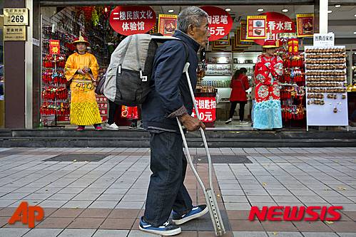 【베이징=AP/뉴시스】중국 통계 당국이 지난해 지니계수가 0.464를 기록해 7년 연속 하락했다고 주장했다.  20일 중국공산당 기관지인 런민르바오(人民日報)는 전날 중국 국가통계국이 2015년 중국의 국내총생산(GDP), 국민소득 등을 발표하면서 지니계수가 지난 2003년 이후 최저치를 기록하고 2009년이후 7년 연속 하락세를 보였다고 밝혔다고 전했다. 다만 정부차원에서 공개된 이런 결과의 신뢰성에 관련된 의문이 중국 안팎에서 꾸준히 제기돼왔다. 한편 최근 공개된 일부 조사 결과는 상위 1%가 전체 자산의 3분의 1을 차지하고 있을 정도로 불평등이 확대되고 있는 것으로 확인됐다. 한 남성이 베이징 도심에서 목발을 짚고 가게 앞을 지나고 있다. 2016.01.20