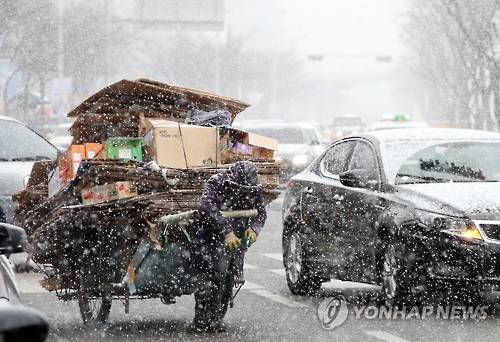 (광주=연합뉴스) 박철홍 기자 = 광주·전남에 내일까지 최고 30㎝의 폭설이 예보된 23일 오후 광주 서구 치평동의 한 도심 거리에서 한 노인이 길거리에서 거둬들인 폐지를 수레에 싣고 눈발을 헤치며 힘겨운 걸음을 내디디고 있다. 2016.1.23     pch80@yna.co.kr
