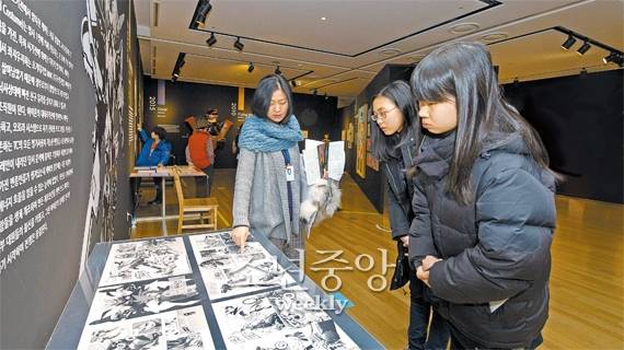 최은영 큐레이터가 백길령(왼쪽)·김나현 독자에게 로봇이 그려진 만화 원고의 특징에 대해 설명하고 있다.