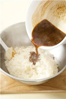 5. 찐 찹쌀에 약식물을 넣어 섞고 대추, 밤, 호박씨, 잣 등을 넣어 다시 쪄서 뜨거울 때 편평한 그릇이나 적당한 그릇에 랩을 깔고 약식을 펴서 꼭꼭 눌러준 다음 한 김 식혀 자른다. (Tip 이때 밤이 다 익을 정도로만 찐다.)