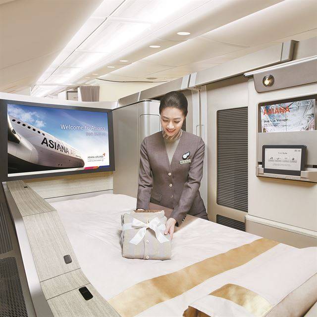 32인치 모니터가 설치된 '퍼스트 스위트'에서 승무원이 침구를 준비하고 있다. 아시아나항공 제공