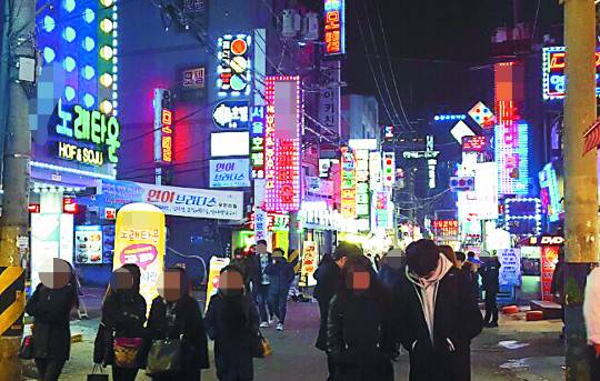 행인들이 22일 오후 10시쯤 번쩍이는 노래방 간판들로 가득한 서울 영등포역 인근 유흥가를 지나고 있다.