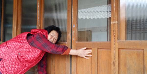 신기촌 마을 한 주민이 마루문을 열려고 하고 있으나 집이 기울어져 꿈쩍도 하지 않고 있다.