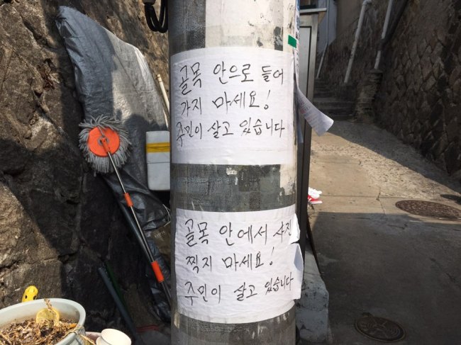 Signs posted on a pole in Ihwa-dong read, “Do not enter the alley,” “Do not take pictures inside the alley. There are people living here.” (Kim Da-sol/The Korea Herald)