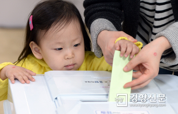 제20대 국회의원선거 투표일인 13일 오전 서울 천연동 주민센터에 마련된 투표소에서 엄마와 함께 온 어린이가 투표용지를 넣고 있다.  | 김정근 기자