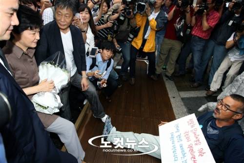 지난 2012년 8월 28일 전태일재단 방문이 무산된 당시 박근혜 새누리당 대선 후보가 서울 종로구 청계천 6가 전태일 다리로 이동해 전태일 열사 동상 앞에서 추모하려 하자 한 쌍용자동차 노조원이 드러누워 이를 거부하고 있다. 박 후보는 당초 서울 창신동에 있는 전태일 재단을 찾아 전태일 열사를 추모할 예정이었으나 "진정성이 없다"는 유가족 측의 반대로 무산됐다. (사진=자료사진/노컷뉴스)