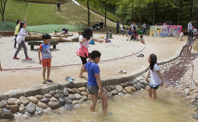 아이들이 뿜어낸 물은 작은 돌과 자갈로 만들어진 아래쪽 웅덩이로 흘러듭니다. 벌써 반팔·반바지 등 여름 옷 차림을 한 아이들은 발을 담그고는 "강가에 놀러온 기분"이라며 즐거워합니다. 규모가 작긴 하지만 주변에 모래도 있고 나무도 있어서 수영장보다 훨씬 좋다고 했습니다. 사진 프리랜서 오종찬