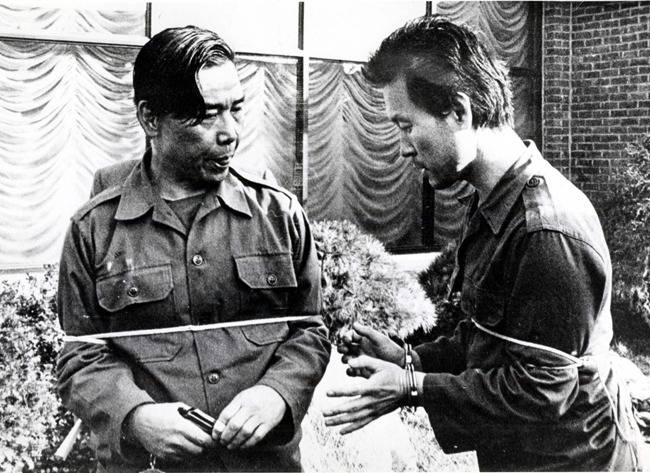 10·26 사건 현장검증에서 김재규가 전속 부관 박흥주의 권총을 뺏어 드는 장면을 재현하고 있다. [동아일보]