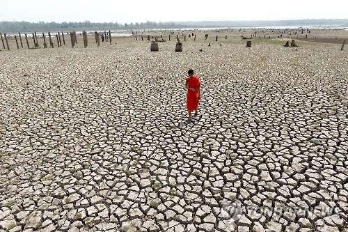 가뭄에 갈라진 길 위를 걷는 태국 승려. 2016.3(EPA=연합뉴스 자료사진)