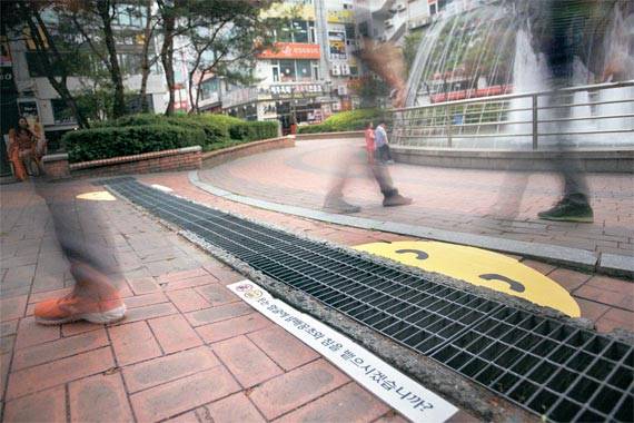지난달 23일 경기도 시흥시 대야동 중심상업지구에 있는 빗물받이 하수구에 부착한 ‘씩~ 웃는 스마일’ 스티커. 시흥시는 이 지역 빗물받이 하수구 78곳을 ‘스마일 존’으로 지정하고 LOUD팀이 제작한 스티커를 부착했다. [제임스 요한슨 객원 사진작가]