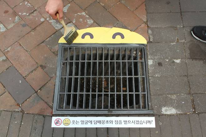 LOUD팀의 작업 모습. 빗물받이 하수구의 크기에 따라 스마일 스티커의 크기를 달리했다. [제임스 요한슨 객원 사진작가]
