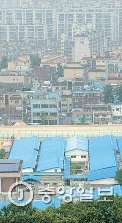 안양교도소는 재건축·이전을 둘러싸고 1990년대 말부터 법무부와 안양시가 마찰을 빚어왔다. 안양교도소 일대는 63년 준공 때 변두리에서 시 중심부가 됐다. 교도소 담장 너머 호계동 주택가가 보인다. [사진 전민규 기자]
