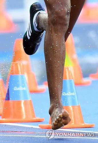 에티오피아 여자 육상선수 에테네쉬 디로(25)가 14일(한국시간) 리우 올림픽 스타디움에서 열린 여자 3,000ｍ 장애물 달리기 예선 3조 경기에서 다른 선수와 충돌해 오른쪽 신발이 찢어지자, 신발을 벗고 경기를 뛰고 있다. (EAP=연합뉴스)