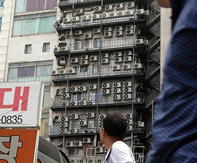 가정용 전기요금 누진제도의 개선을 요구하는 시민들의 목소리가 높아지고 있다. 서울 남대문시장을 지나던 시민이 건물 외벽에 촘촘히 설치된 에어컨 실외기들을 바라보고 있다. 김경호 선임기자 jijae@hani.co.kr