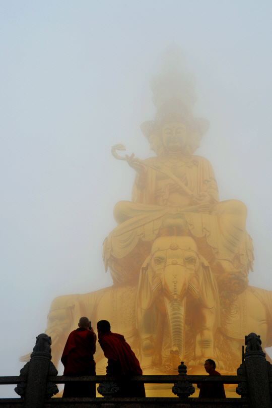 안개가 일순 걷히면서 드러난 어메이산 정상의 십방보현보살좌상 앞에서 간쑤성에서 왔다는 승려들이 기념사진을 찍고 있다. 높이 48m의 좌상은 순금으로 만든 24만 장의 금박을 입혀 놓았다.
