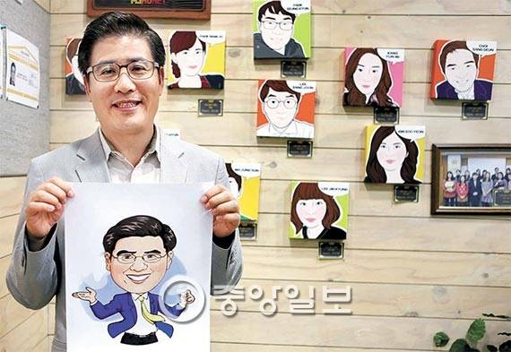 조영탁 대표가 지난달 22일 서울 구로구 휴넷 사옥에 걸린 직원들의 캐리커처 앞에서 자신의 캐리커처를 들고 섰다. 그는 “외부 전문가에게 의뢰해 직원들의 캐리커처를 그려 선물한다”고 말했다. [사진 김춘식 기자]