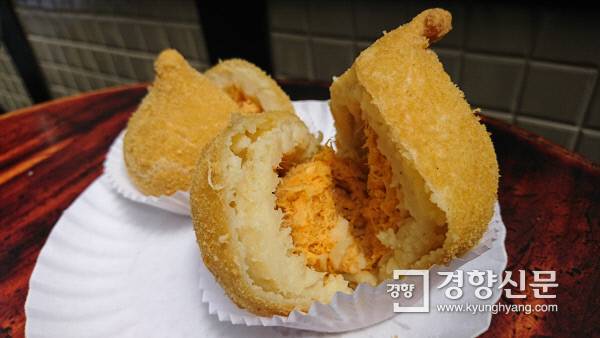 길거리에서 산 ‘코시냐’를 가르면 감자 반죽과 다진 닭고기살이 나온다.