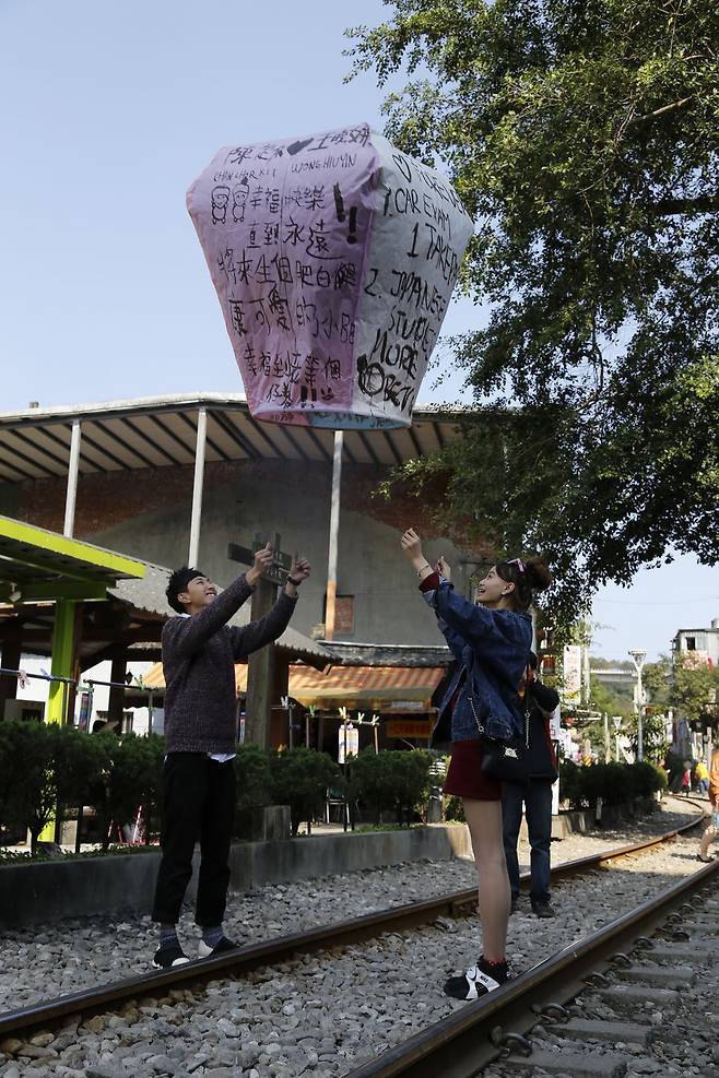 스펀에서 한 커플이 소원을 꼭꼭 눌러 적은 천등을 날리고 있다.