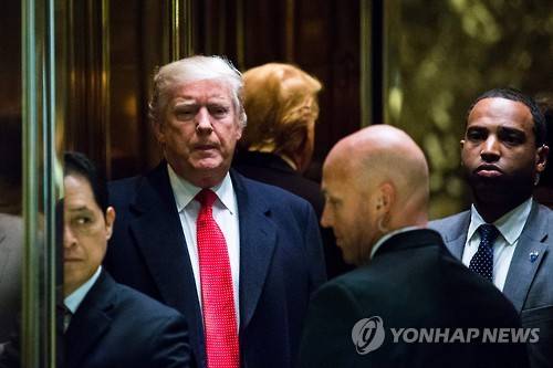 (AFP=연합뉴스) 도널드 트럼프(가운데 빨간 넥타이 한 사람) 미국 대통령 당선인이 6일(현지시간) 오전 뉴욕의 트럼프타워에 들어서 엘리베이터를 타고 있다.