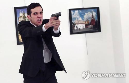 터키 앙카라법원이 26일 안드레이 카를로프 터키주재 러시아대사 살해사건의 보도금지를 결정했다. 사진은 19일 앙카라의 한 사진전시회에서 터키 경찰관 메블뤼트 메르트 알튼타시가 러시아대사를 쏜 후 참석자들에게 총을 겨눈 모습. [AP=연합뉴스]