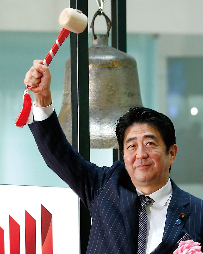 아베 신조 일본 총리가 2013년 12월30일 도쿄 증권거래소 폐장 행사에 참석, 종을 친 후 채를 든 채 포즈를 취하고 있다. © AP 연합