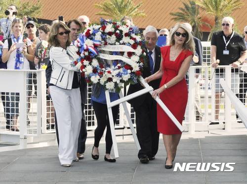 【AP/뉴시스】 = 50년전인 1967년 1월 27일 아폴로 1호의 화재로 빠져나오지 못하고 숨진 3명의 우주비행사를 추모하는 행사에서 유족들이 전시장 입구에 세울 화환을 헌정하고 있다.  플로리다주 케네디 우주센터 방문자회관에서 열린 이 행사에는 미우주항공국(NASA)의 아폴로 계획에 참가했던 많은 우주비행사와 관계자들 수백명이 참석했다.