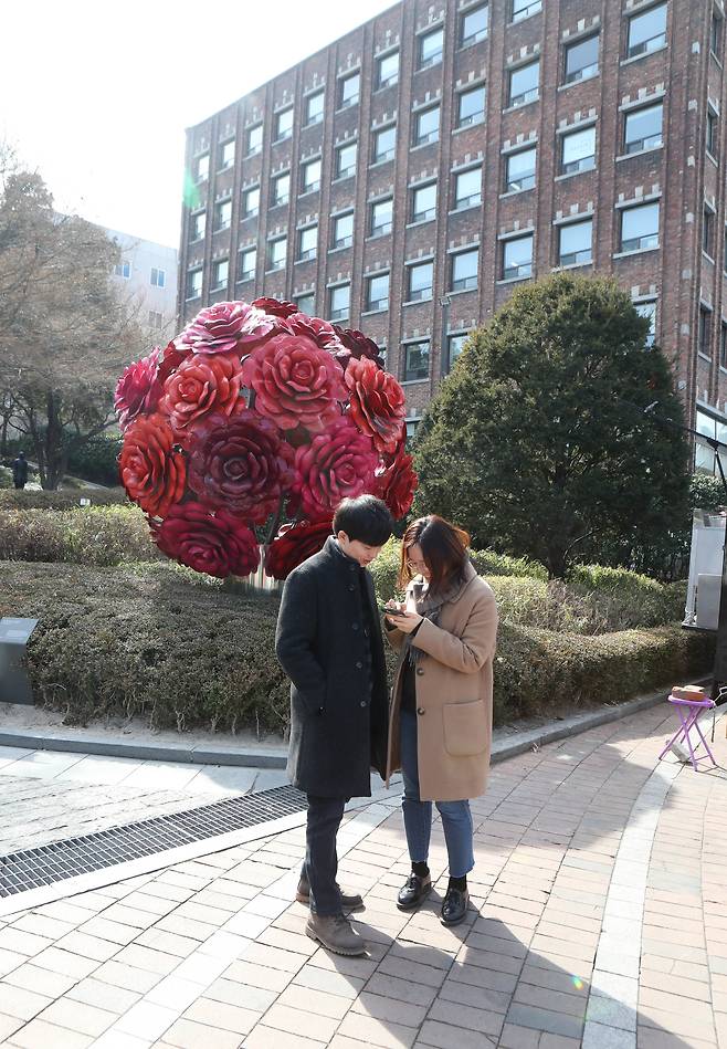 한 여성이 최정화의 조각 '장미빛 인생' 앞에서 포켓몬 게임을 하고 있다. 신인섭 기자