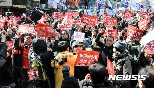 【서울=뉴시스】홍찬선 기자 = 헌재가 박근혜 대통령의 탄핵을 인용을 결정했다. 즉 사상 첫  탄핵심판으로 파면당한 대통령으로 기록되게 됐다.   10일 오후 서울 종로구 헌법재판소 앞 도로에서 박 대통령의 탄핵 인용 소식에 시민들이 피켓을 들고 기뻐하고 있다. 2017.03.10.    mania@newsis.com