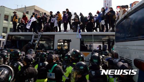 【서울=뉴시스】홍찬선 기자 = 헌재가 박근혜 대통령의 탄핵을 인용을 결정했다. 즉 사상 첫  탄핵심판으로 파면당한 대통령으로 기록되게 됐다.   10일 오후 서울 종로구 헌법재판소 앞 도로에서 탄핵 인용에 항의하는 시민들이 태극기를 들고 헌재로 진입을 시도하기 위해 경찰버스 지붕위에 올라가 있다. 2017.03.10.    mania@newsis.com