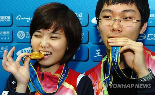 (광저우=연합뉴스) 22일 중국 광저우기원에서 열린 아시안게임 바둑 혼성복식에서 우승한 박정환과 이슬아가 금메달을 깨물고 있다. 2010.11.22 <한국기원>      xyz@yna.co.kr