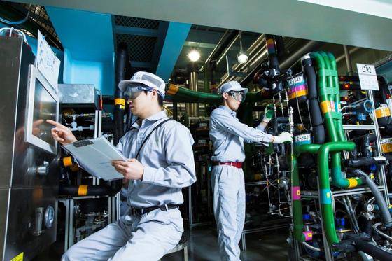 대전 SK바이오텍 공장에서 직원들이 파이프라인으로 물질을 흘려보내는 방식으로 약효물질을 배합하는 저온연속공정 설비를 살펴보고 있다. [사진 SK바이오텍]