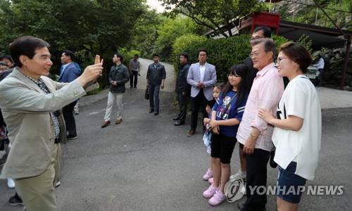 (양산=연합뉴스) 최병길 기자 = 문재인 대통령이 21일 오후 경남 양산시 매곡동 사저에 도착해 마을을 찾아온 한 가족과 다정한 모습으로 기념사진을 찍고 있다. 휴대전화로 사진을 찍어주는 사람은 주영훈 경호실장이다. 구겨진 남방, 편한 바지, 등산화 차림으로 나온 문 대통령 모습이 눈길을 끈다. 2017.5.21  choi21@yna.co.kr  (끝)