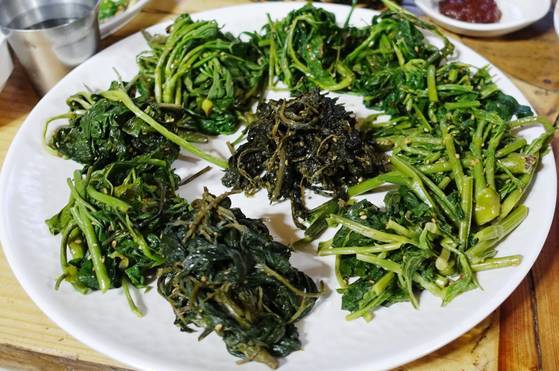 깊고 깊은 산골 음식점 겸 펜션 ‘오대산 내고향’ 산채정식의 핵심인 산나물 10종 무침. ①개미취 묵나물(사진 가운데) ②단풍취묵나물(사진 6시 방향/이후 시계방향) ③오가피순 ④곰취 ⑤음나무순 ⑥모싯대 ⑦산갓 ⑧강활나물 ⑨두릅순 ⑩취나물이다. 산나물 맛의 개성을 살리기 위해 들기름, 참깨가루, 2000도 숯가마에서 24시간 구운 소금만으로 무쳤다고 한다.