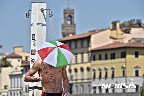 【피렌체=AP/뉴시스】이탈리아 깃발 색깔의 우산 모자를 쓴 남성이 1일(현지시간) 피렌체의 노천 샤워 시설에서 물을 맞으며 더위를 식히고 있다. 이탈리아 대부분 지역에 폭염이 강타하면서 적색 경보가 내려졌다. 2017.08.02