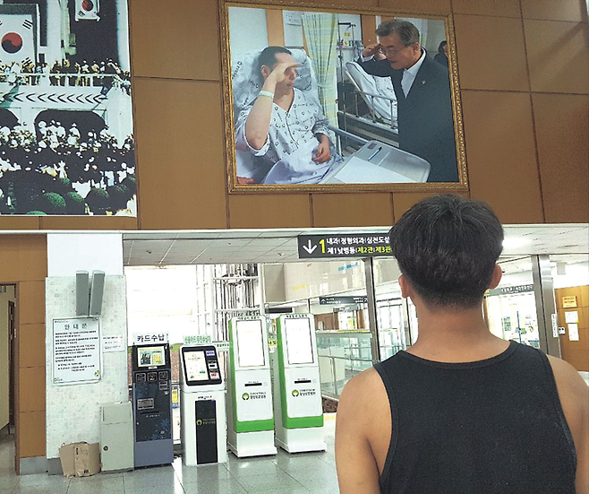 보훈병원에서 문재인 대통령과 부상 장병이 경례하는 사진을 바라보는 김한철씨 © 사진= 김한철 제공