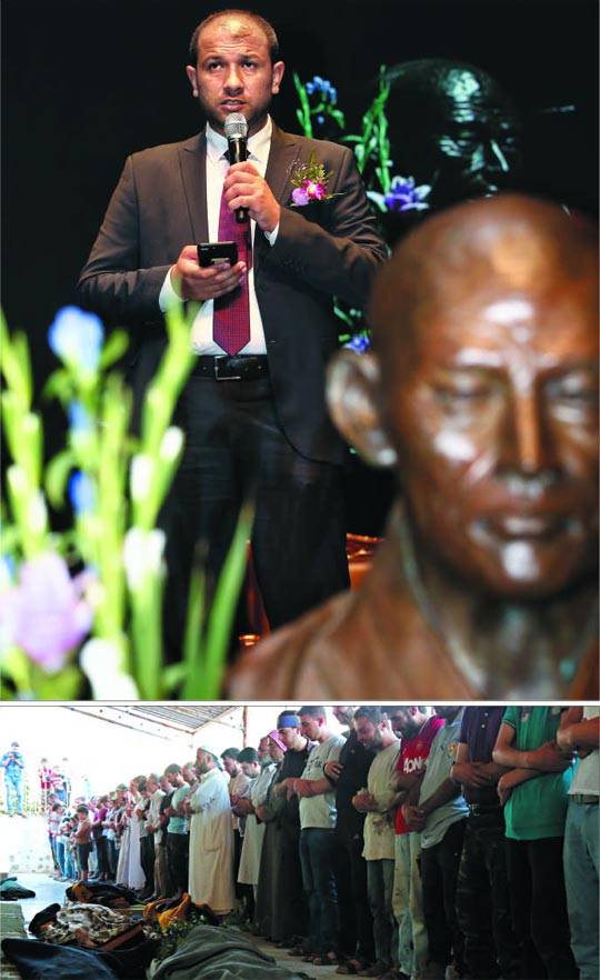 평화상 꽃다발과 동료의 장례식 - 시리아 민간구호단체 '하얀헬멧' 대표 라이드 알 살레(위 사진)가 12일 오후 만해대상 시상식에서 수상 소감을 발표하고 있다. 그는 이날 시상식장으로 이동하던 중 시리아 현지로부터“대원 7명 피살”이란 급보를 받았다. 시상식장 단상에 앉아서도 휴대폰으로 현장 상황을 보고받고 수습 대책을 지시하던 그는 결국 이날 밤 나머지 일정을 취소하고 시리아 현지로 날아갔다. 아래 사진은 이날 살해된 하얀헬멧 대원 7명의 장례식이 시리아 현지에서 치러지고 있는 모습. /조인원 기자·EPA 연합뉴스