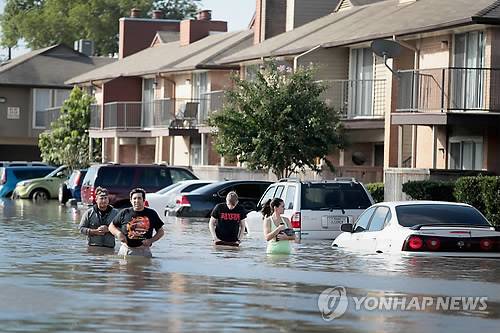 (휴스턴<미 텍사스주> AFP/게티이미지=연합뉴스) 열대성 폭풍으로 약해졌지만 엄청난 비구름을 몰고 온 허리케인 '하비'가 30일(현지시간) 오전 루이지애나 주로 장소를 바꿔 다시 상륙하면서 24명이 추가로 숨지는 등 공식 확인된 사망자가 35명으로 늘어난 것으로 나타났다.      사진은 이날 텍사스주 휴스턴의 주택가에서 주민들이 물이 허리까지 찬 도로에서 구조를 기다리는 모습.      bulls@yna.co.kr