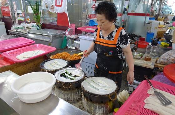 메밀부침을 부치고 있는 중앙시장 ‘신선칼국수’ 여주인 임연숙씨. 오른쪽에는 미리 만들어둔 총떡, 왼쪽에는 부침이 쌓여 있다.